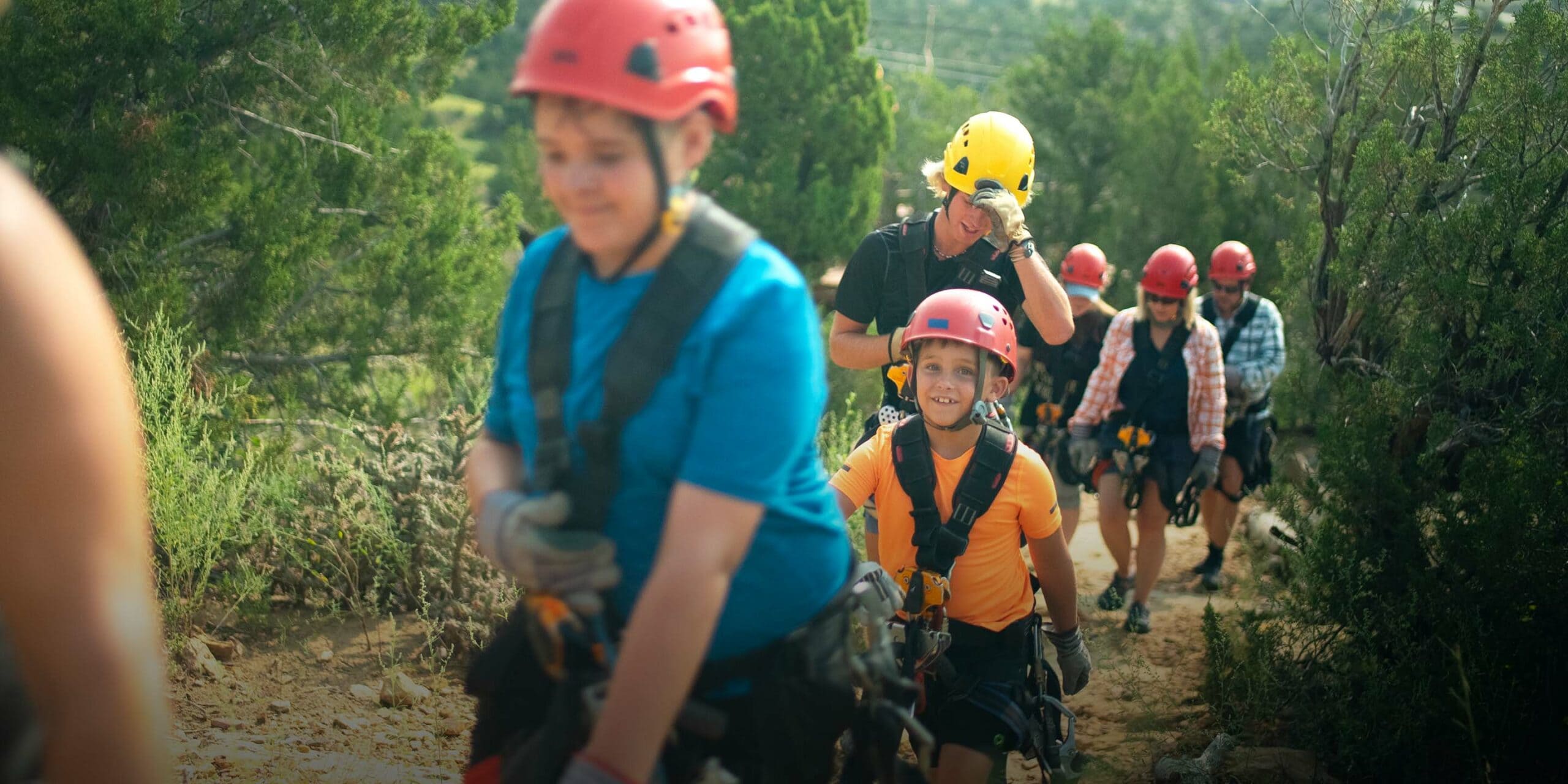 A group in helmets and harnesses walking the trail to the zipline